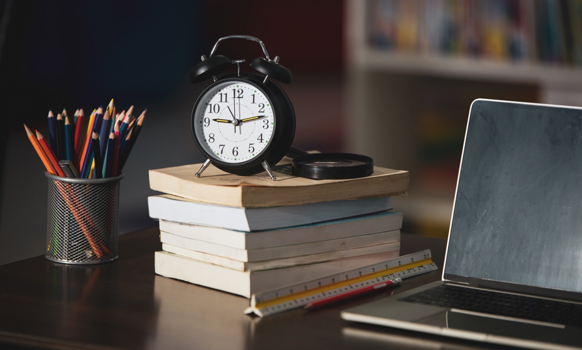 Book,laptop,pencil,clock on wooden table in library,education le